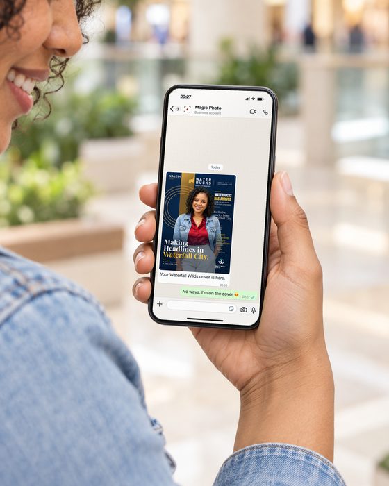 A guest in a denim jacket smiles down at her phone, where a WhatsApp chat from Magic Photo shows her Waterbucks cover with the message Your Waterfall Wilds cover is here.